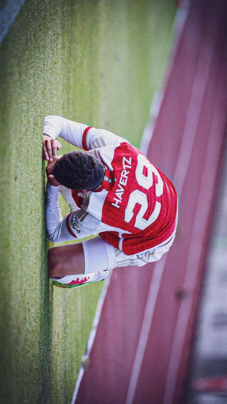 a soccer player leaning against the wall with his hands on his head and looking down