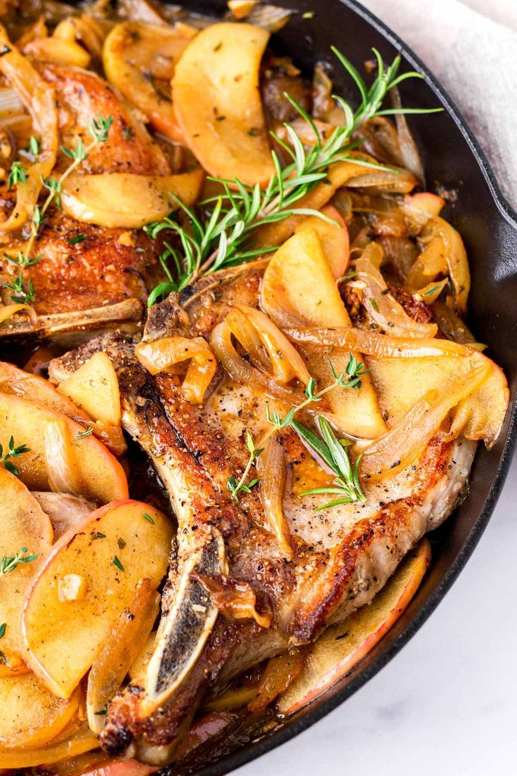 a skillet filled with meat and potatoes on top of a white tablecloth next to a fork