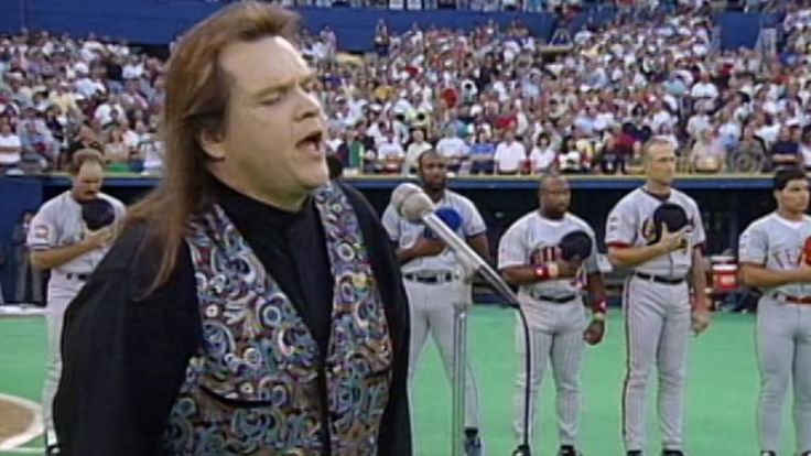 a man standing in front of microphones at a baseball game