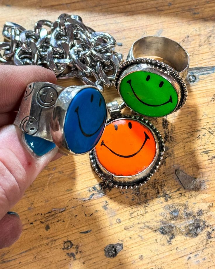 a hand holding a ring with three smiley faces on it and several chains around it