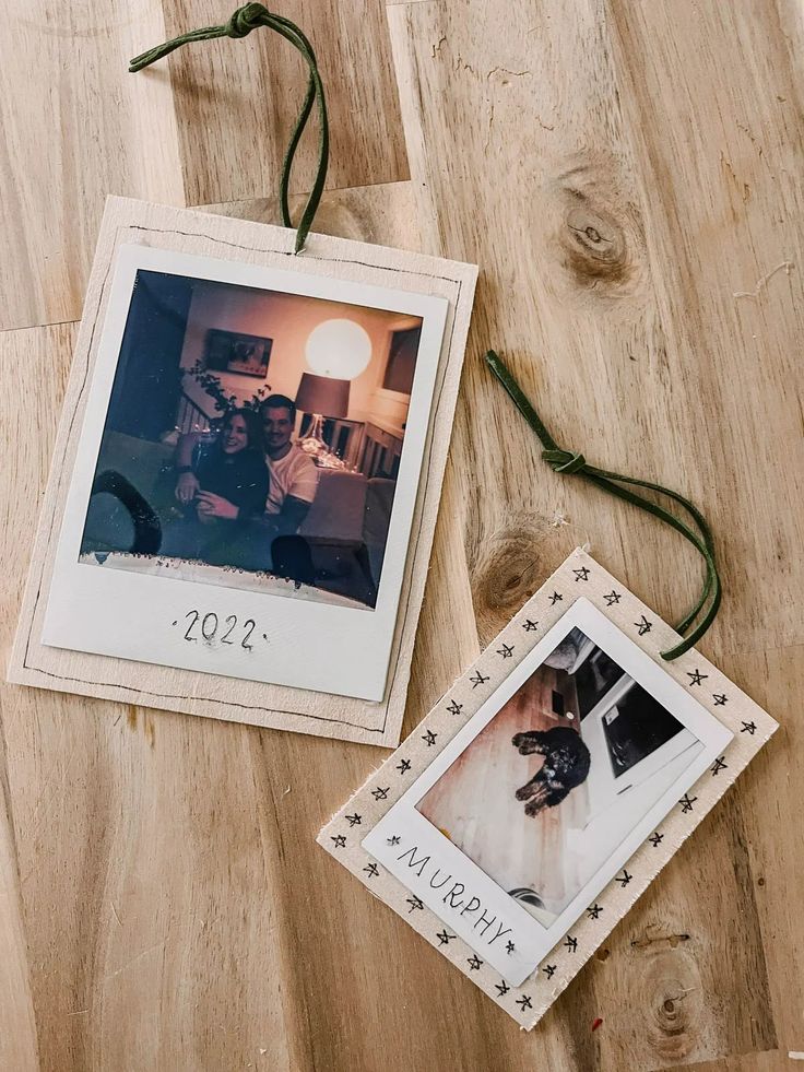 two polaroid pictures are sitting on a wooden floor next to twine string lights