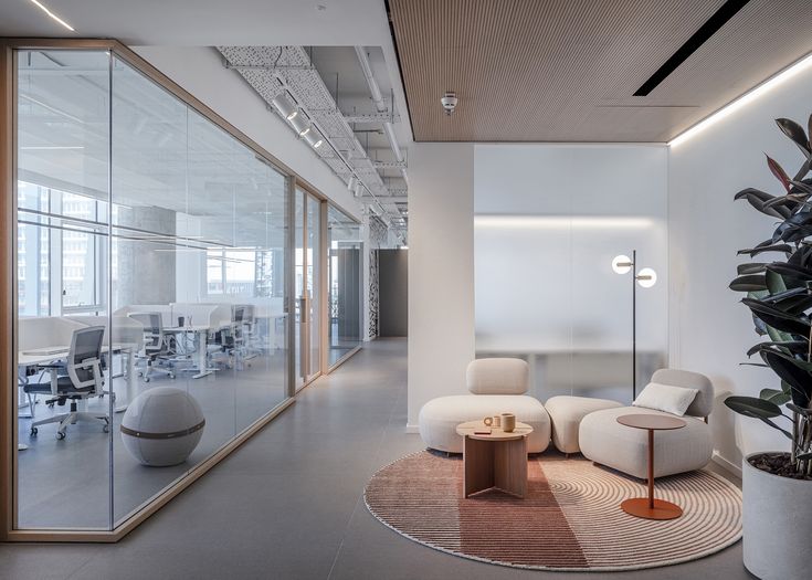 an office with white chairs and plants in the corner, along with large glass windows