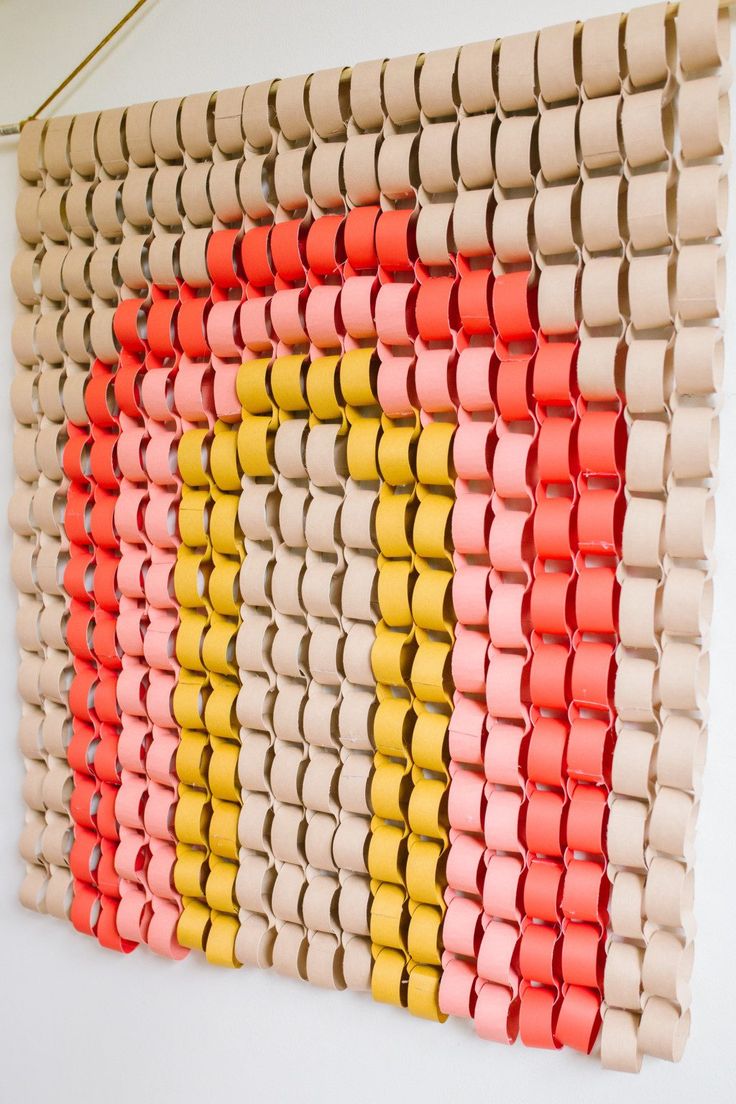 a multicolored wall hanging made out of rolled up toilet paper and some tape