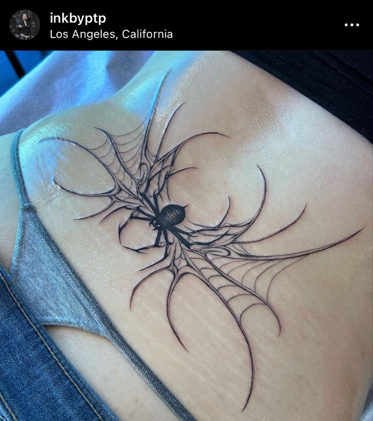 a spider web tattoo on the back of a woman's stomach