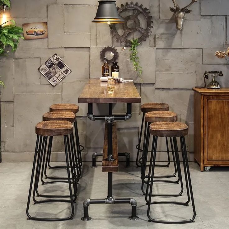 a wooden table with four stools in front of it and a clock on the wall