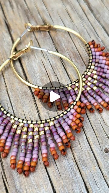 a close up of a pair of hoop earrings on a wooden surface with beads hanging from the hoop