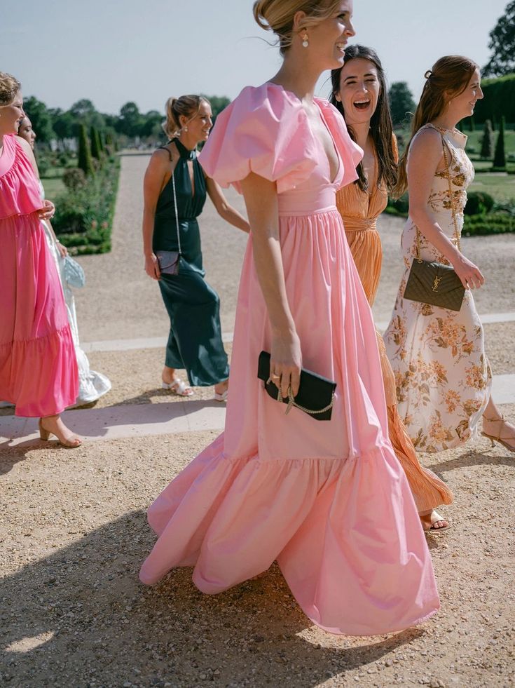 two women in long dresses are talking to each other while others walk by on the sidewalk