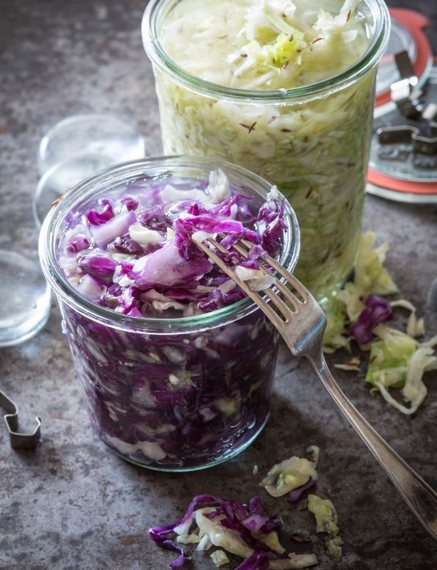 two glass jars filled with food sitting on top of a table next to spoons