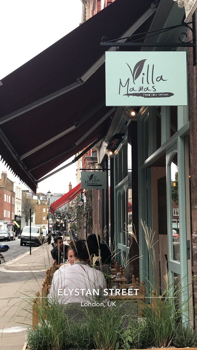 a woman sitting on a bench in front of a building with an awning over it