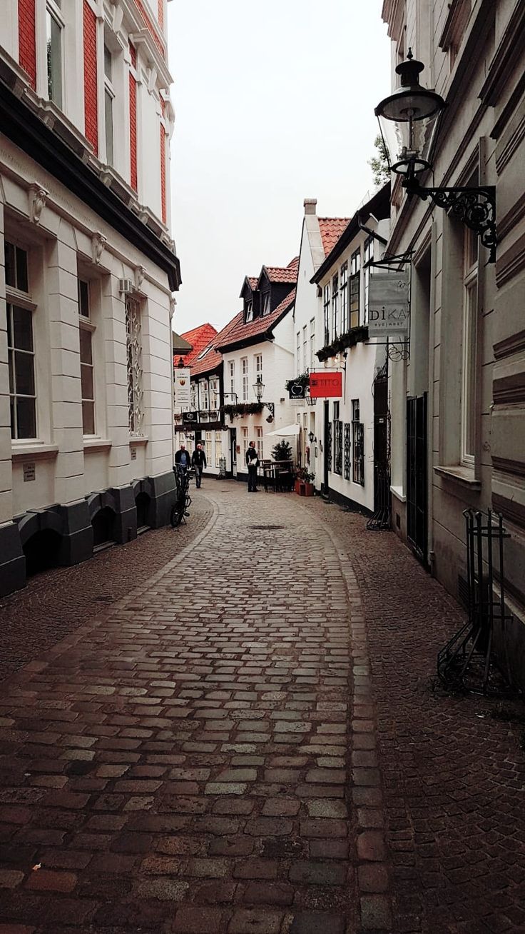 a cobblestone street lined with white buildings