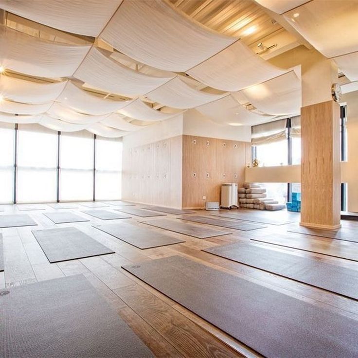 an empty room with yoga mats on the floor and large windows in the back ground