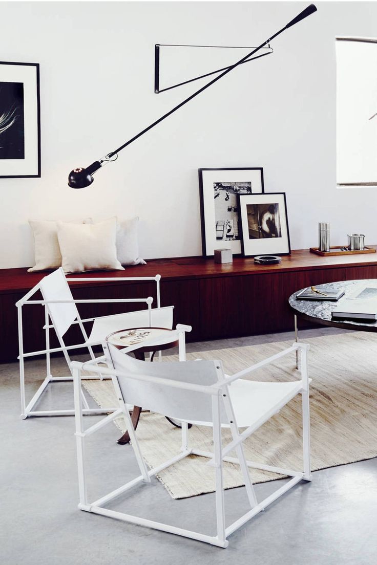 a living room filled with white furniture and pictures on the wall above it's coffee table