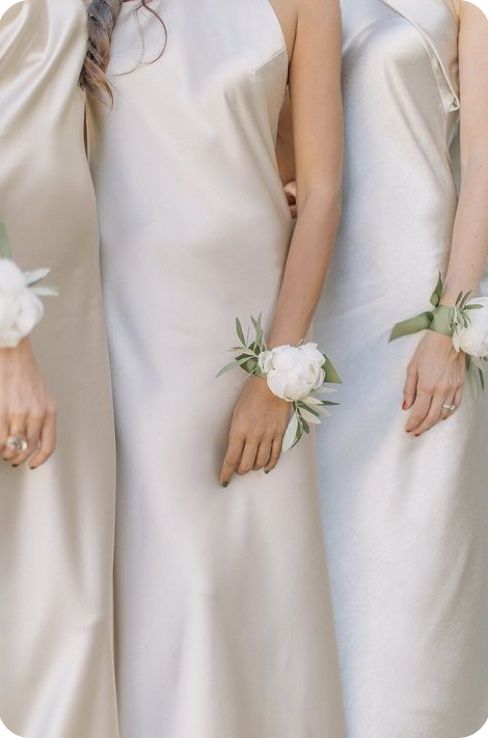 three bridesmaids in white gowns with flowers on their wrist ties and hair combs