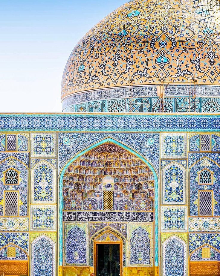 an ornate building with blue and gold tiles on the walls, in front of a large dome