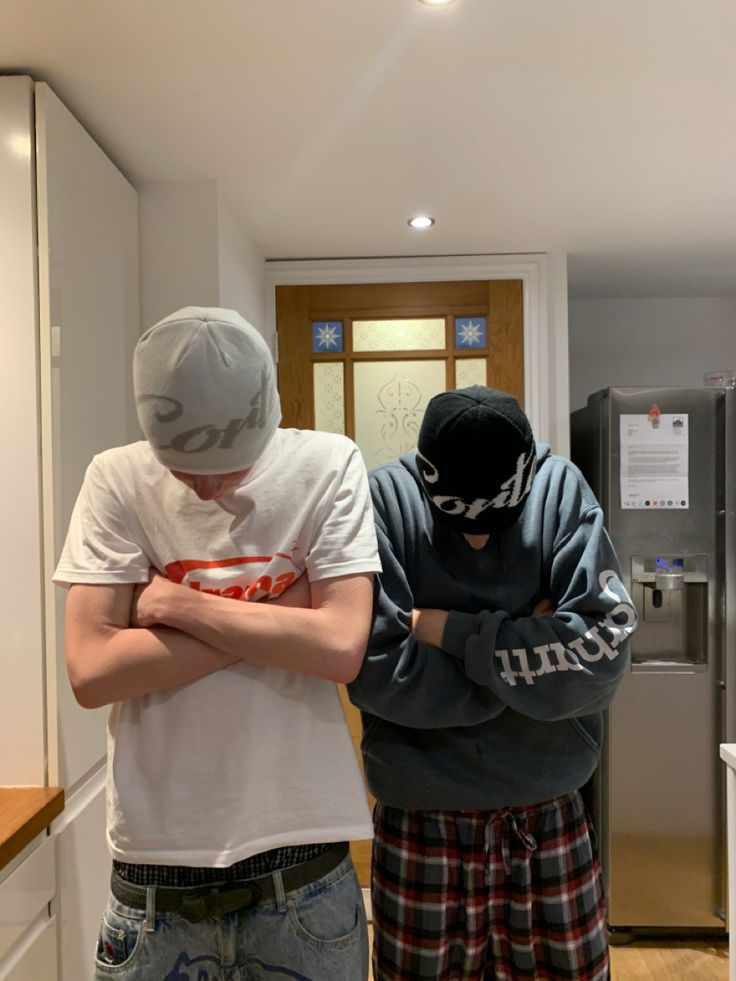 two young men standing next to each other in a kitchen