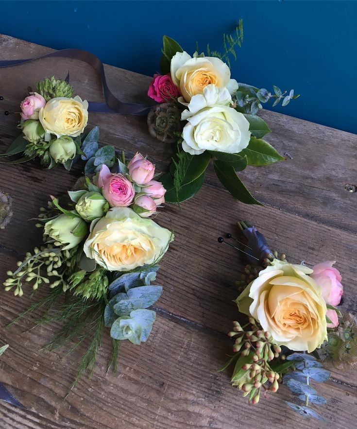 three bouquets of flowers sitting on top of a wooden table next to each other