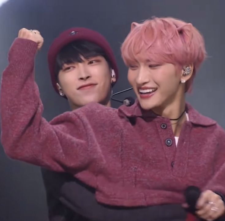 two young men with pink hair are posing for the camera and one is holding his arm up