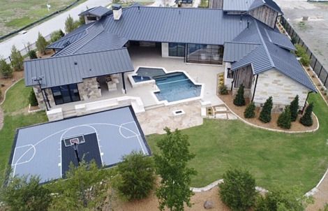 an aerial view of a house with a basketball court in the yard and swimming pool