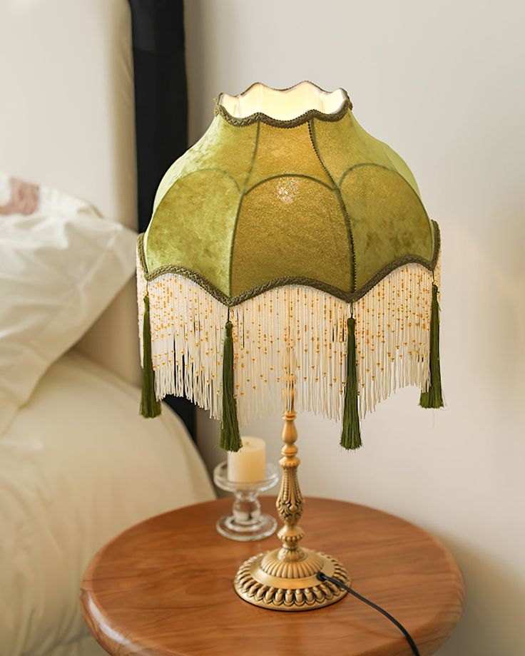 a table with a lamp on top of it next to a night stand and bed