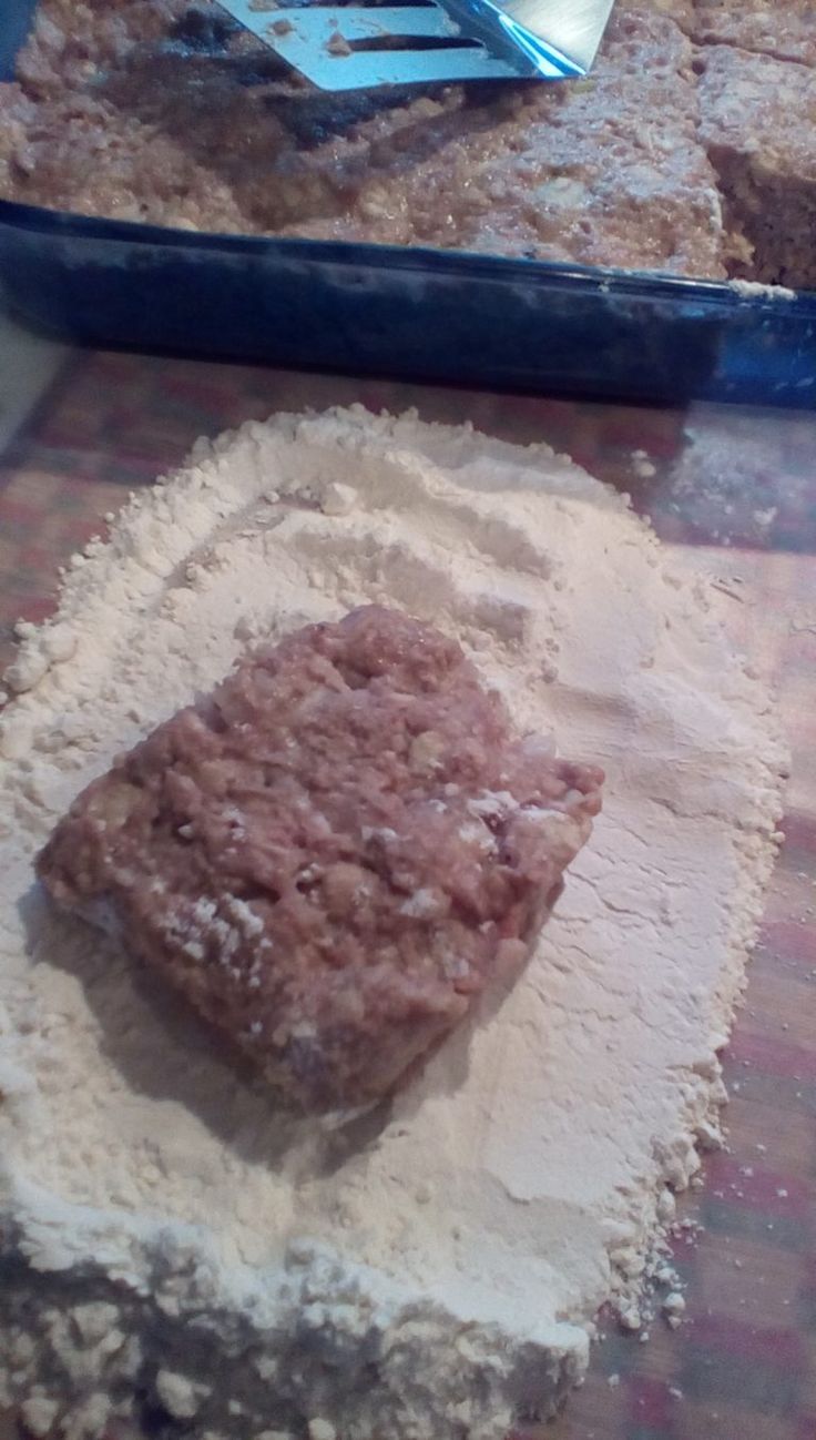 a piece of cake sitting on top of a table next to a pan with powdered sugar