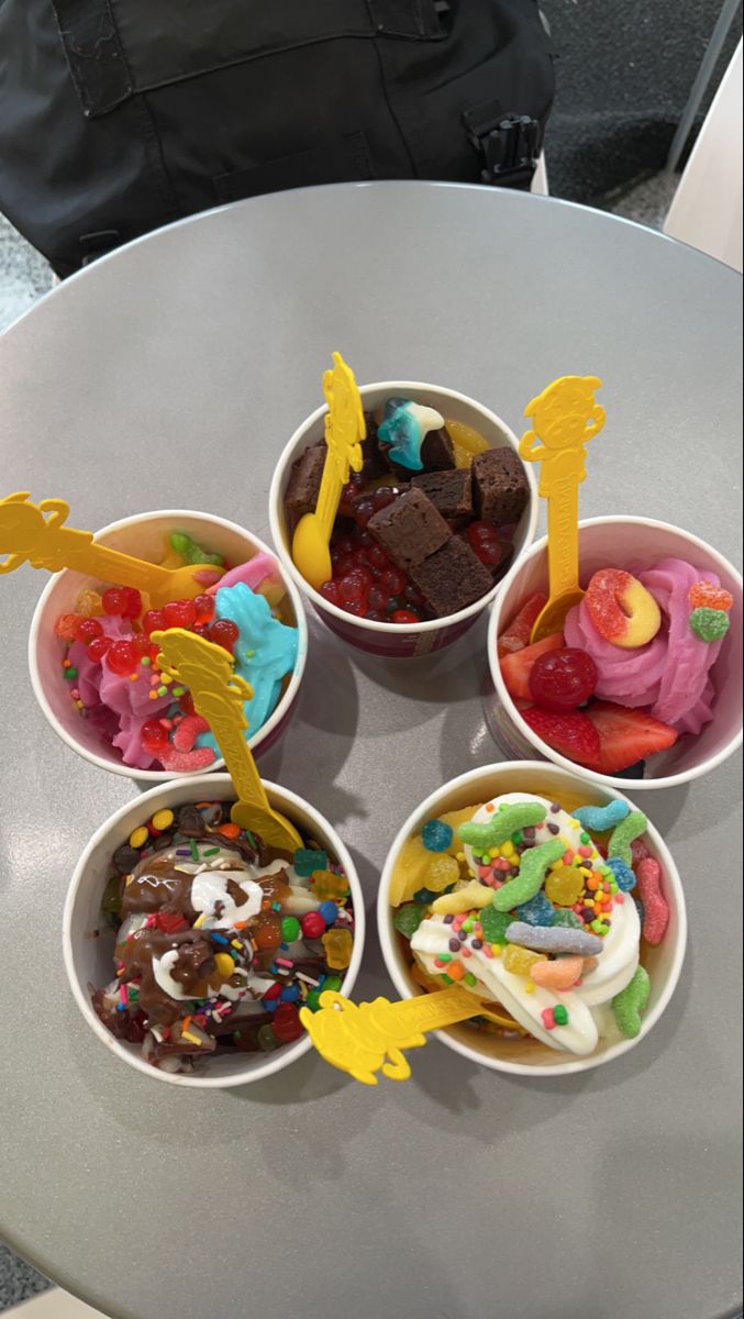 four bowls filled with different types of desserts on top of a white table next to a black bag