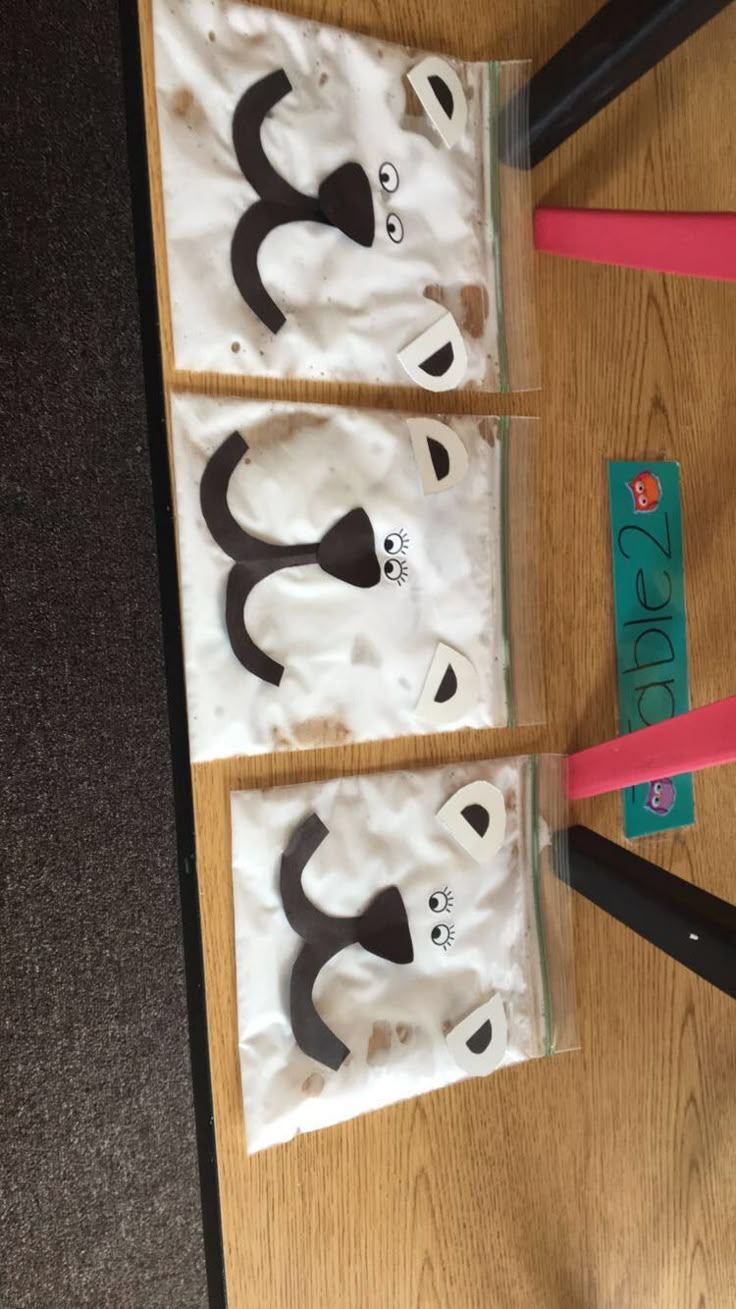 three bags with panda faces on them sitting on a table next to scissors and tape