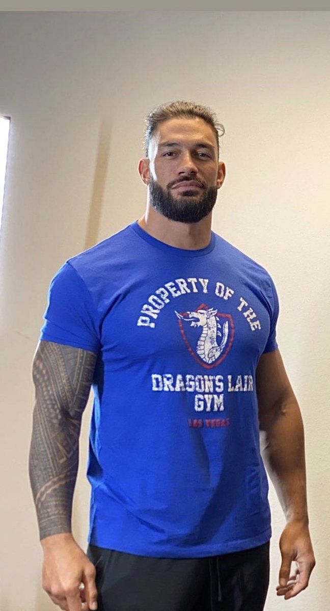 a man standing in front of a mirror wearing a blue t - shirt with the words property of the dragon's lar gym on it