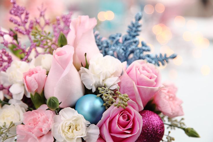 a vase filled with pink and white flowers on top of a table next to a blue ornament