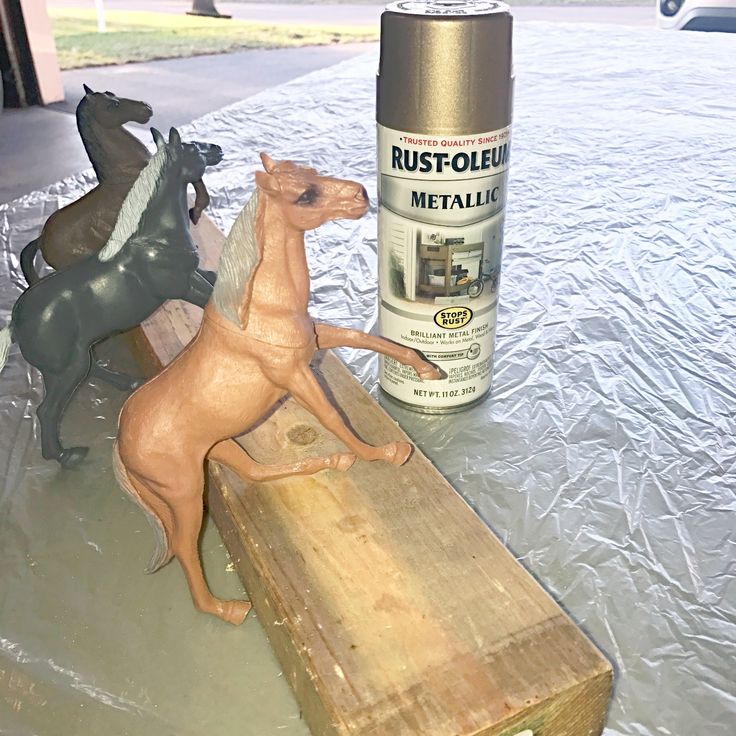 a horse statue next to a spray paint can on a piece of plywood wood