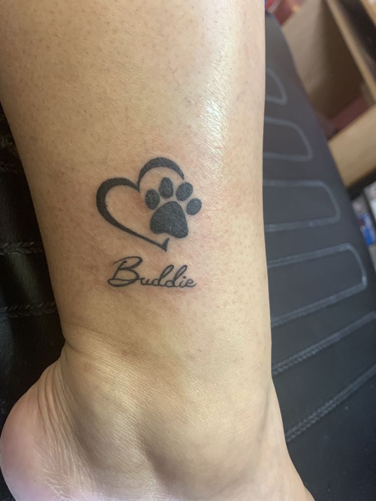 a dog paw and heart tattoo on the ankle that says, bullie with an arrow in it