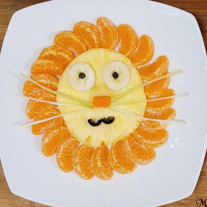 a white plate topped with orange slices and a lion face