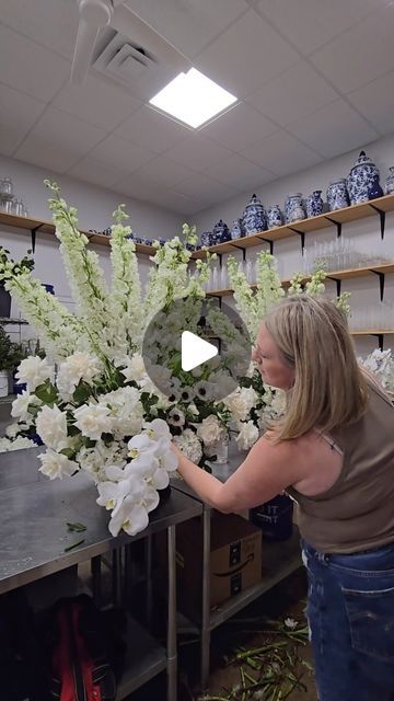 a woman arranging white flowers in a vase