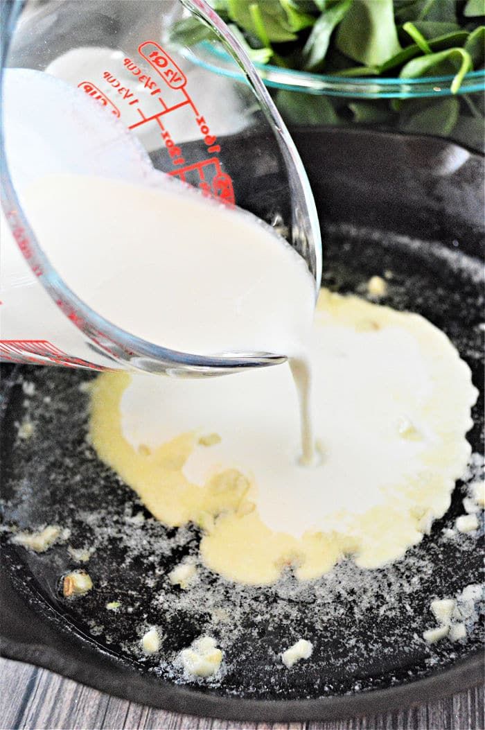 someone pouring milk into a skillet filled with food