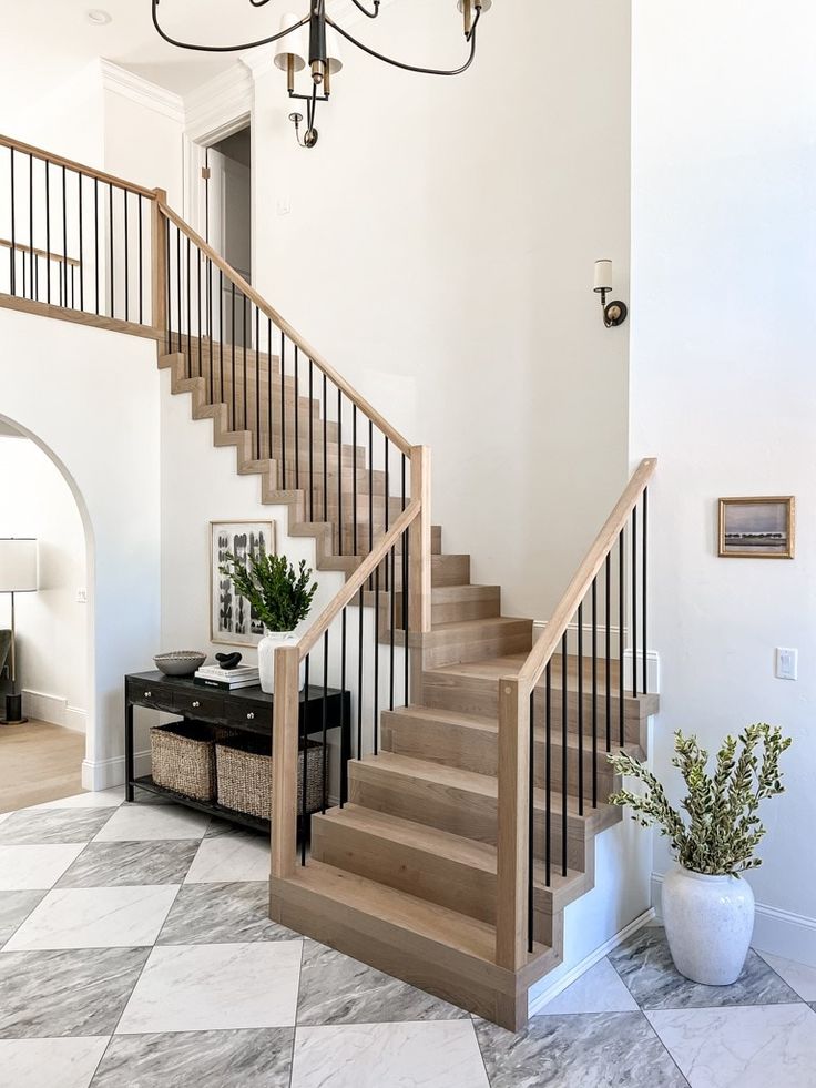 there is a staircase in the middle of this living room with white walls and marble flooring