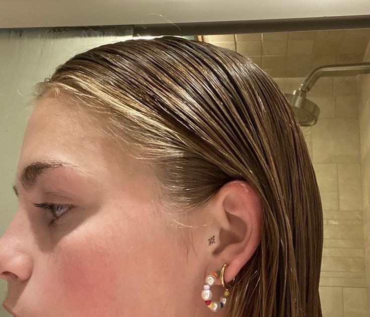 a close up of a person with ear piercings on their ears and in front of a mirror