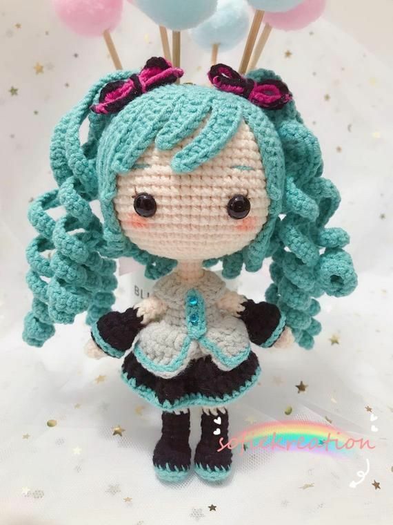 a crocheted doll with blue hair and black shoes holding balloons in her hands