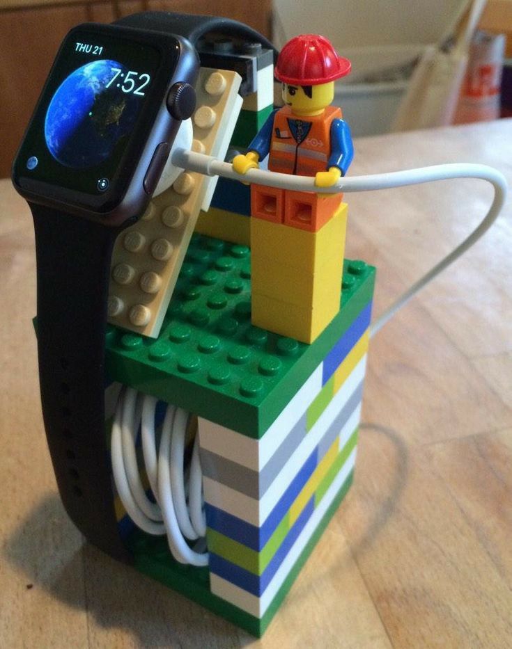 an apple watch sits on top of a lego block with a construction worker attached to it