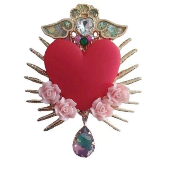 Ex-voto boho chic red heart brooch "Vibrant Red Heart Brooch" Add a touch of color and elegance to your outfit with this beautiful red heart brooch. Featuring a bright red heart at its center, this handmade accessory is adorned with delicate pink roses and gold accents, giving it a sophisticated and charming look. The brooch is topped with a sparkling heart-shaped crystal and sparkling angel wings, symbolizing protection and love. Suspended from the heart is a stunning drop-shaped crystal, addin Boheme Chic, Heart Brooch, Handmade Accessories, Vibrant Red, Angel Wings, Red Heart, Gold Accents, Pink Roses, Favorite Jewelry