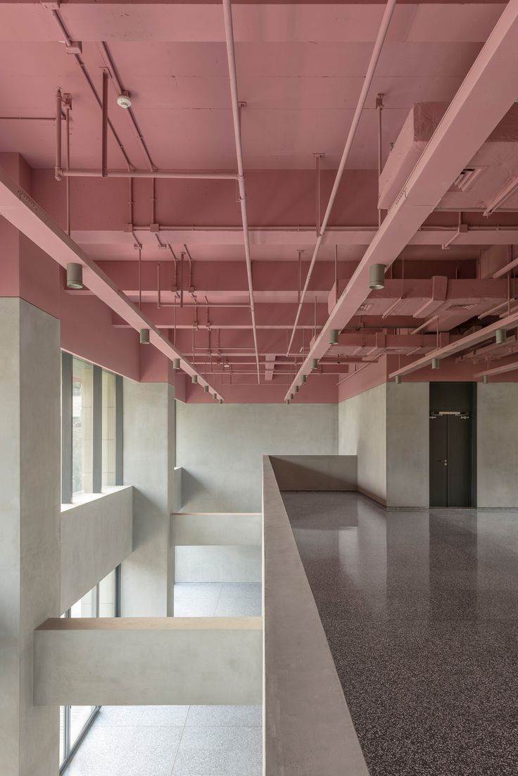 an empty room with pink paint on the ceiling and concrete flooring in front of it