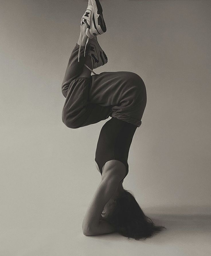 a woman is doing a handstand on one leg with her feet in the air