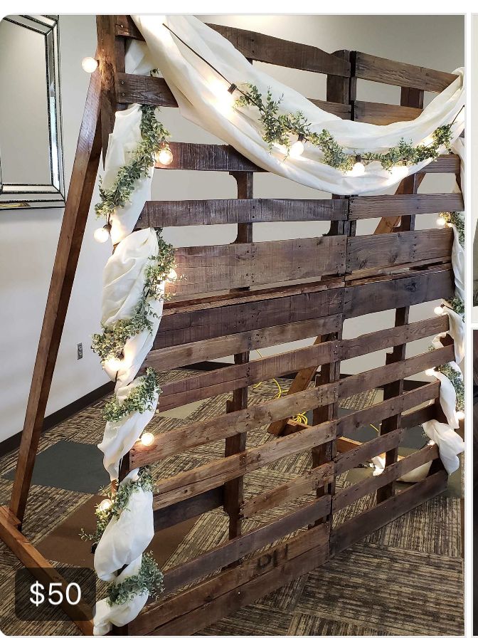 an old pallet is decorated with lights and greenery