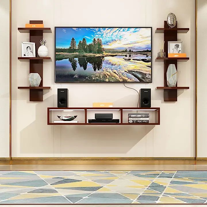 a large television mounted to the side of a wall next to bookshelves and vases