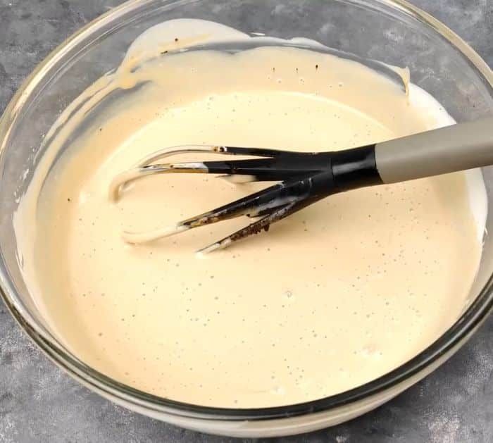 a whisk in a glass bowl filled with batter