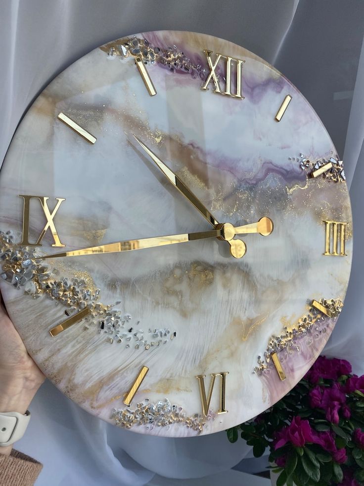 a marble clock with gold hands and roman numerals on the face is displayed