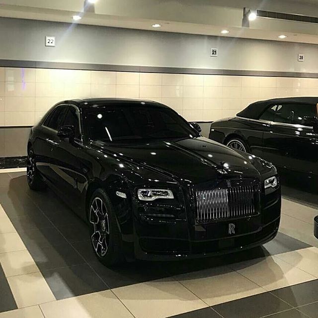 two black rolls royces are parked in a showroom