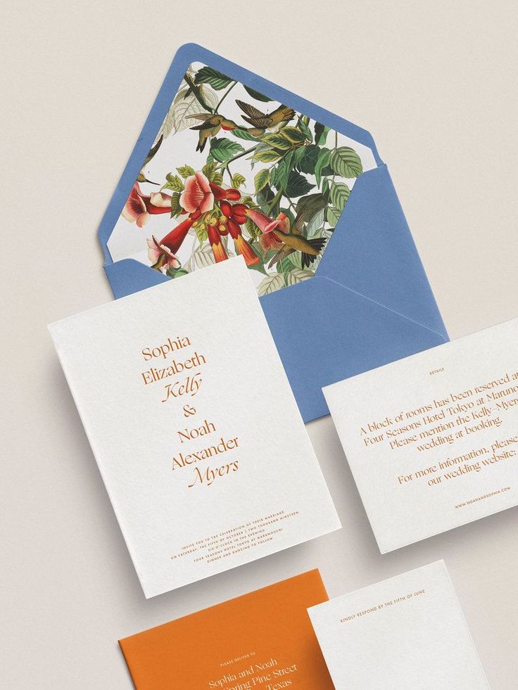 the wedding stationery is laid out on top of an envelope and in between two cards