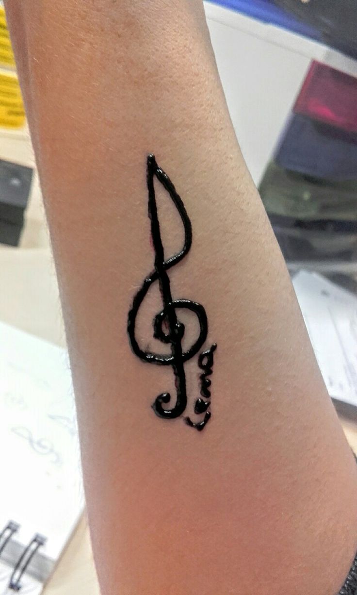 a black ink tattoo on the arm of a person with a musical note in it