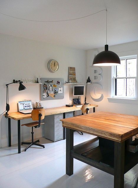 an office with two desks and a computer on top of it, in front of a window