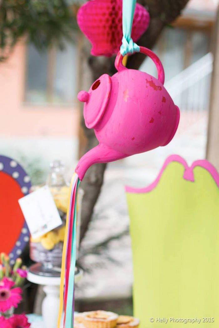 a pink teapot hanging from a blue string next to a table with other items on it