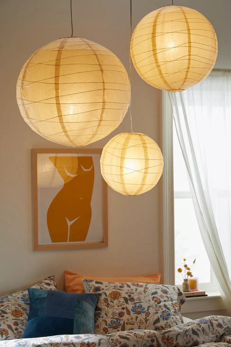 three paper lanterns hanging from the ceiling above a couch in a living room with pillows on it